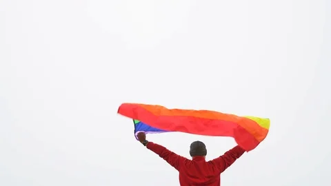 Man raise rainbow flag in hard wind Stock Footage 92408439