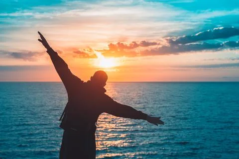Man with raised hands standing on the cliffs edge feeling freedom like a bird on Stock Photos