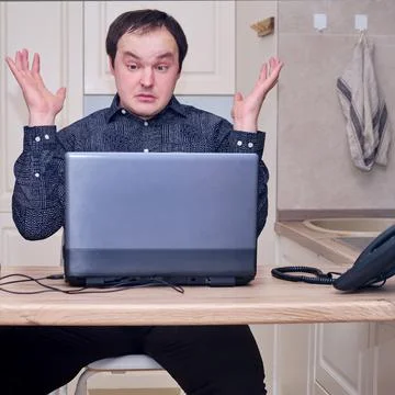 The man raised his hands in frustration while working on the computer from ho Stock Photos
