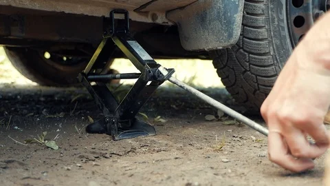 The man raises the car with a jack Stock Footage 109060975
