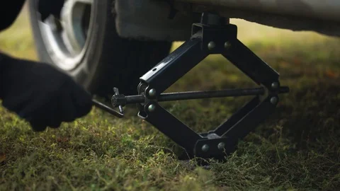 A man raises a car using a jack. 库存影片 125694168