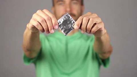 Man raises in front of him on outstretched hands condom, holding it by corners Video stock 94926763