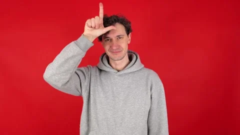 Man raises hand making loser gesture, L sign on forehead, teasing Stock Footage 304747464