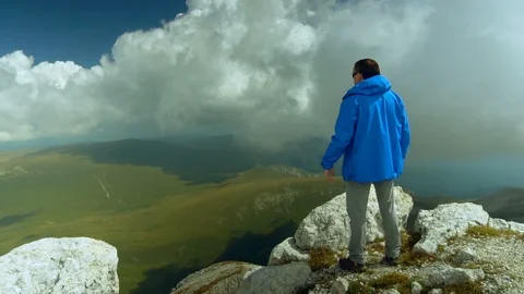 Man raises hands up standing back on mountain top morning. No face male Stock-Footage 99428324