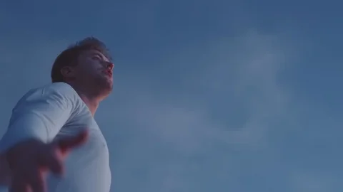 A man raises his hands up, standing on a mountain top, above the clouds and Stock Footage 99370290