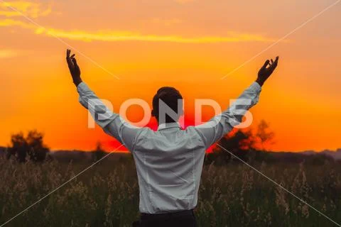A man raises his hands to the sun Stock Photos