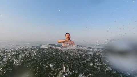 A man raises splashes of water early in the morning on the sea. Slow motion.. Stock-Footage 259737529