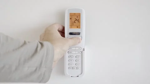 A man raises the temperature of the air conditioner using a remote control Video stock 254343862