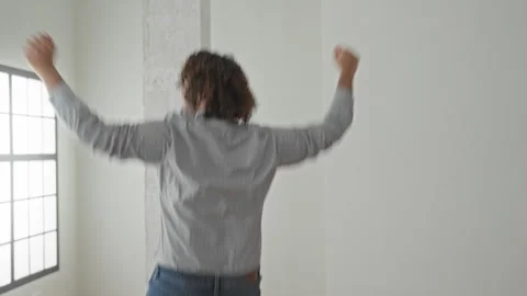 Man raising arms toward window in empty building interior wearing shirt and.. Stock Footage 337405064