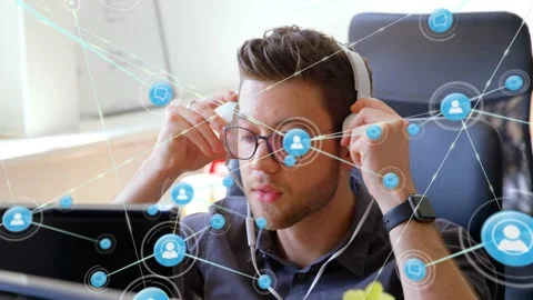 Man raising headphones in tech office, sparking blue network nodes linking Stock Footage 328348317
