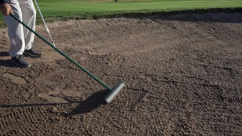A man raking a bunker or sand trap at a golf course Stock Footage 165279200