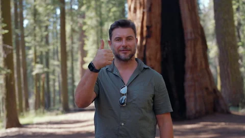 Man ranger pointing thumbs up standing in the woods among the trees Stock Footage 295001747