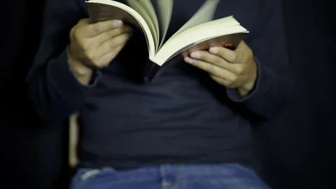 Man Rapidly Flipping Through Book Pages in a Dimly Lit Room at Night Stock Footage 272476286