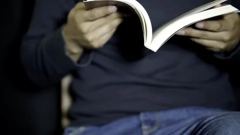 Man Rapidly Flipping Through Book Pages in a Dimly Lit Room at Night Stock Footage 272476743