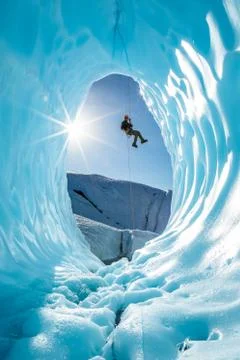 Man rappelling into entrance of glacier ice cave in the mountains of Alaska Stock Photos