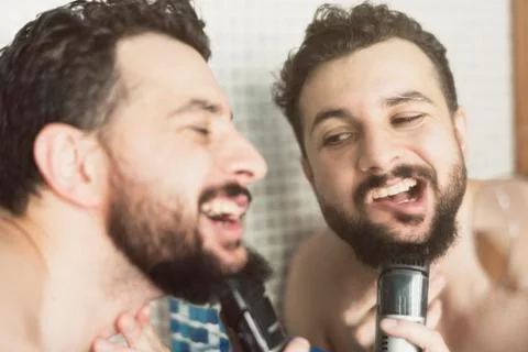 Man with razor machine cuts his beard Foto stock