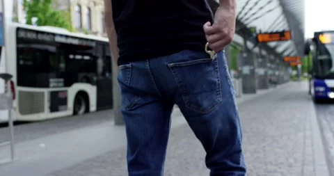 Man Reaching Into Back Pocket at Urban Bus Station, City Transit Hub, Low Angle Stock Footage 341328402