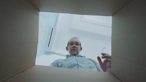 Man reaching into a box with both hands, grabbing something with focus and .. Stock Footage 295193725