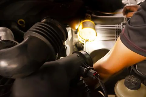 A man is reaching into engine compartment of car to remove some broken parts Stock Photos
