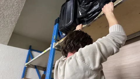 Man reaching up to high warehouse shelf using rack structure, storage and Stock Footage 337110620