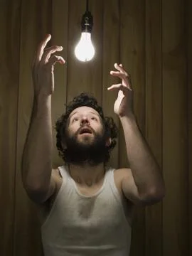 Man reaching up to light bulb Foto stock