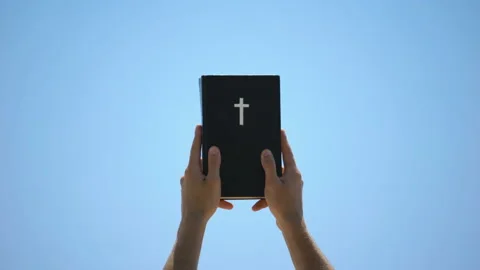 Man reaching out hands to sky holding bible, new testament, ten commandments Video stock 112637915
