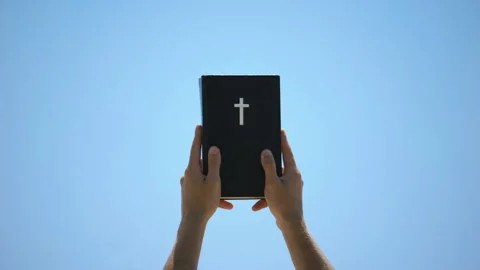 Man reaching out hands to sky holding bible, new testament, ten commandments Video stock 112651307