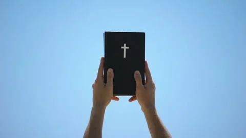 Man reaching out hands to sky holding bible, new testament, ten commandments Video stock 112656069
