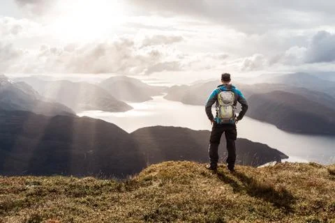 Man reaching summit enjoying freedom. Stunning view to coastal mountains and Stock Photos