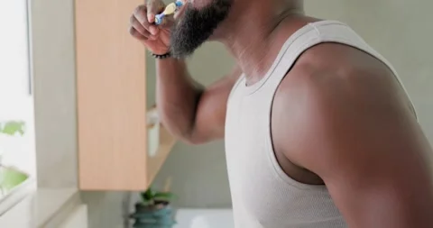 Man reaching for toothpaste, dispensing onto blue brush, brushing teeth for Stock Footage 338064324