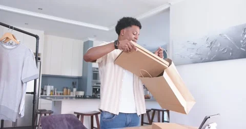 Man reaching toward boxes, packing items into brown bag while animated checklist Stock Footage 342596887