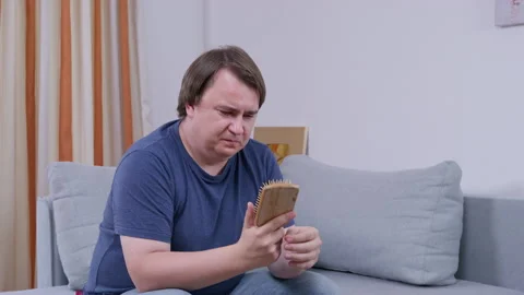 Man reacting with frustration while browsing smartphone on couch in casual Stock Footage 309492463