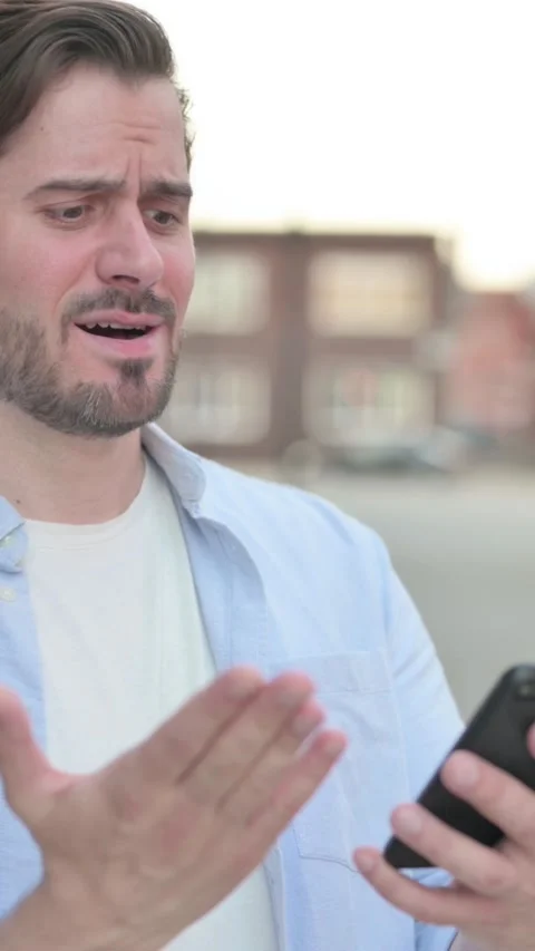 Man Reacting to Loss on Smartphone while Standing Outdoor, Vertical Video Video stock 339665693