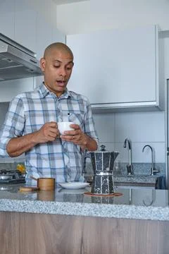 Man reacting with surprise while making morning coffee in kitchen Stock-Fotos