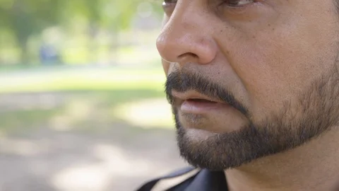 A man reacts to a migraine headache while at a park - shot on RED Stock Footage 124719867