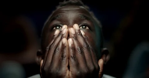 Man reacts to a scary movie by holding his hands over his mouth. Stock Footage