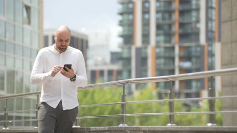 Man reacts unhappily while texting on his phone in the city 스톡 동영상 208912981