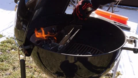 Man readies grill igniting flames for barbecue Experience fiery ambiance as Stock-Footage 270504637
