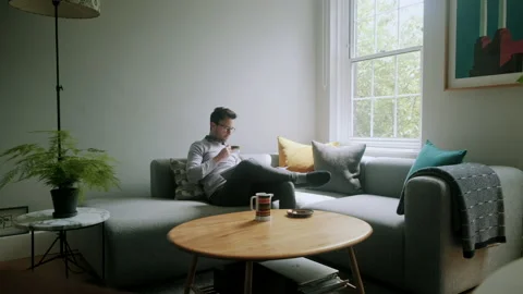 Man reading and sipping tea in living room Stock Footage 130635282