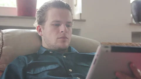 Man reading an article on his tablet and drinking tea Stock Footage 40660634