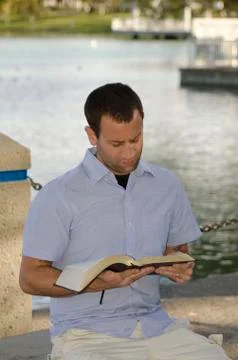 Man reading the Bible at the lake. Stock Photos
