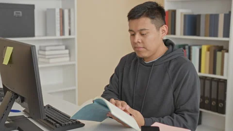 Man reading a blue book, turns page at building study desk with keyboard an.. Stock Footage 337356165