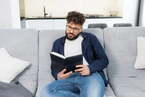 Man reading book and deeply thinking on sofa Stock Photos