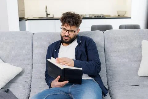 Man reading book and deeply thinking on sofa Stock Photos