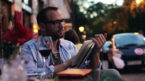 Man reading a book and drinking wine in the restaurant Stock Footage 33697392