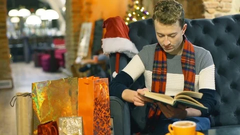 Man reading book and drinking coffee in the festive restaurant, steadycam shot Video stock 71323505