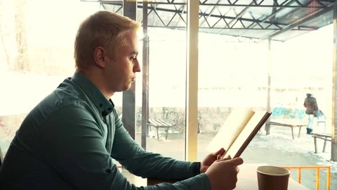 Man reading a book and drinking coffee Stock Footage 84284504