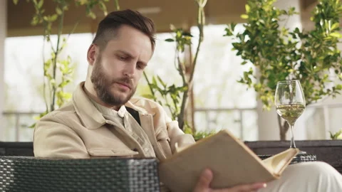 Man Reading Book and Drinking Glass of White Wine in Reastaurant or Bar Indoors Stock Footage 210423039