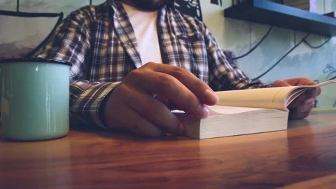 Man reading a book and drinking coffee in cafe Stock Footage 246628021