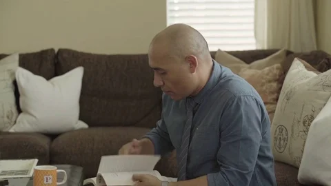 Man reading a book and having coffee at home 스톡 동영상 83186385